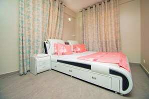 A bedroom with a bed, nightstand, and a small bedside table. - TANZANITE APARTMENT (Kwa Mchina Mwanzo)
