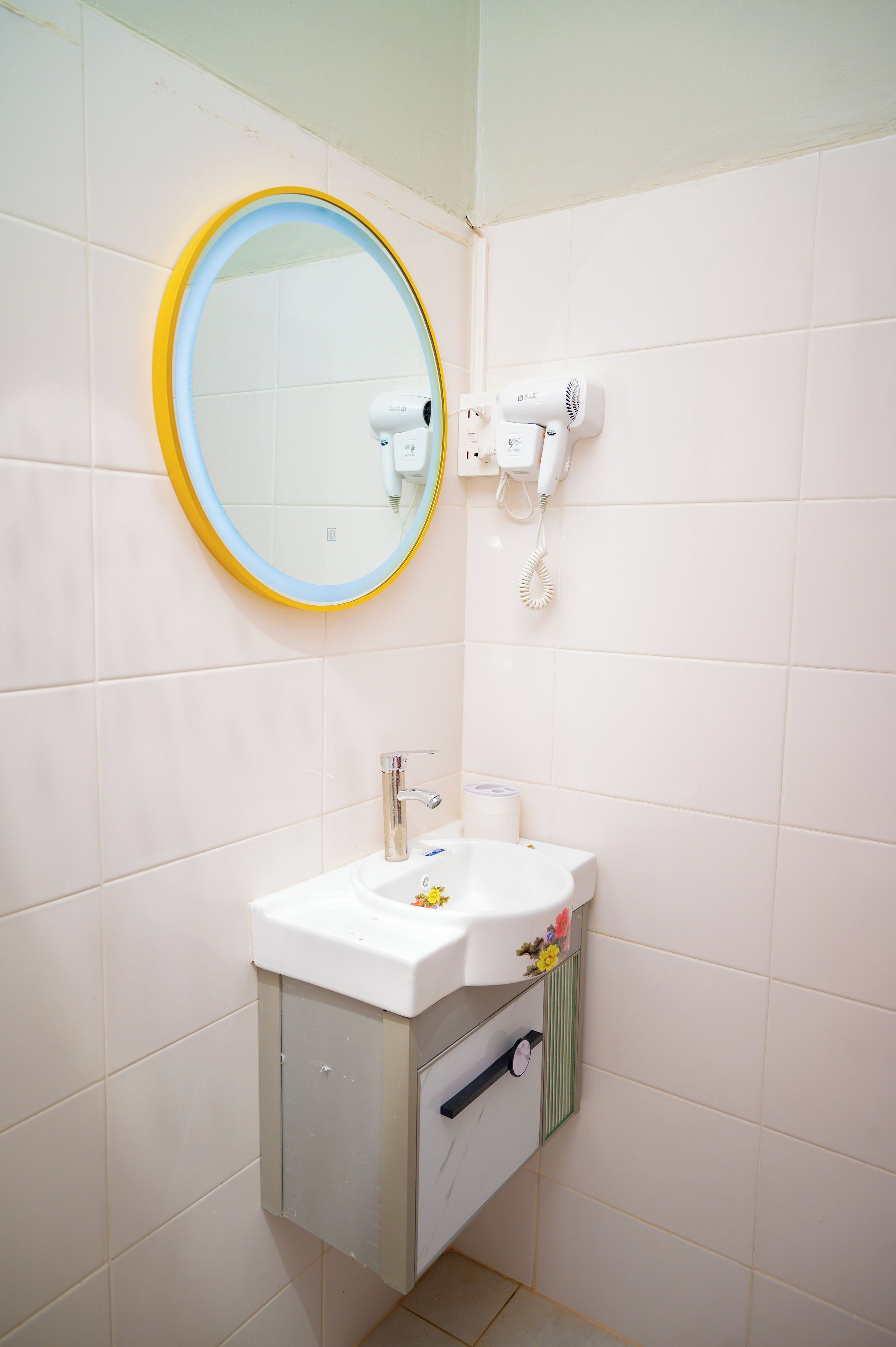 Une salle de bain équipée d’un lavabo, d’un miroir et d’un sèche-cheveux.