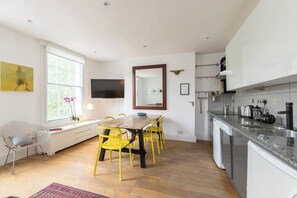 Eine moderne Küche mit weißen Schränken, einem Holztisch und gelben Stühlen.