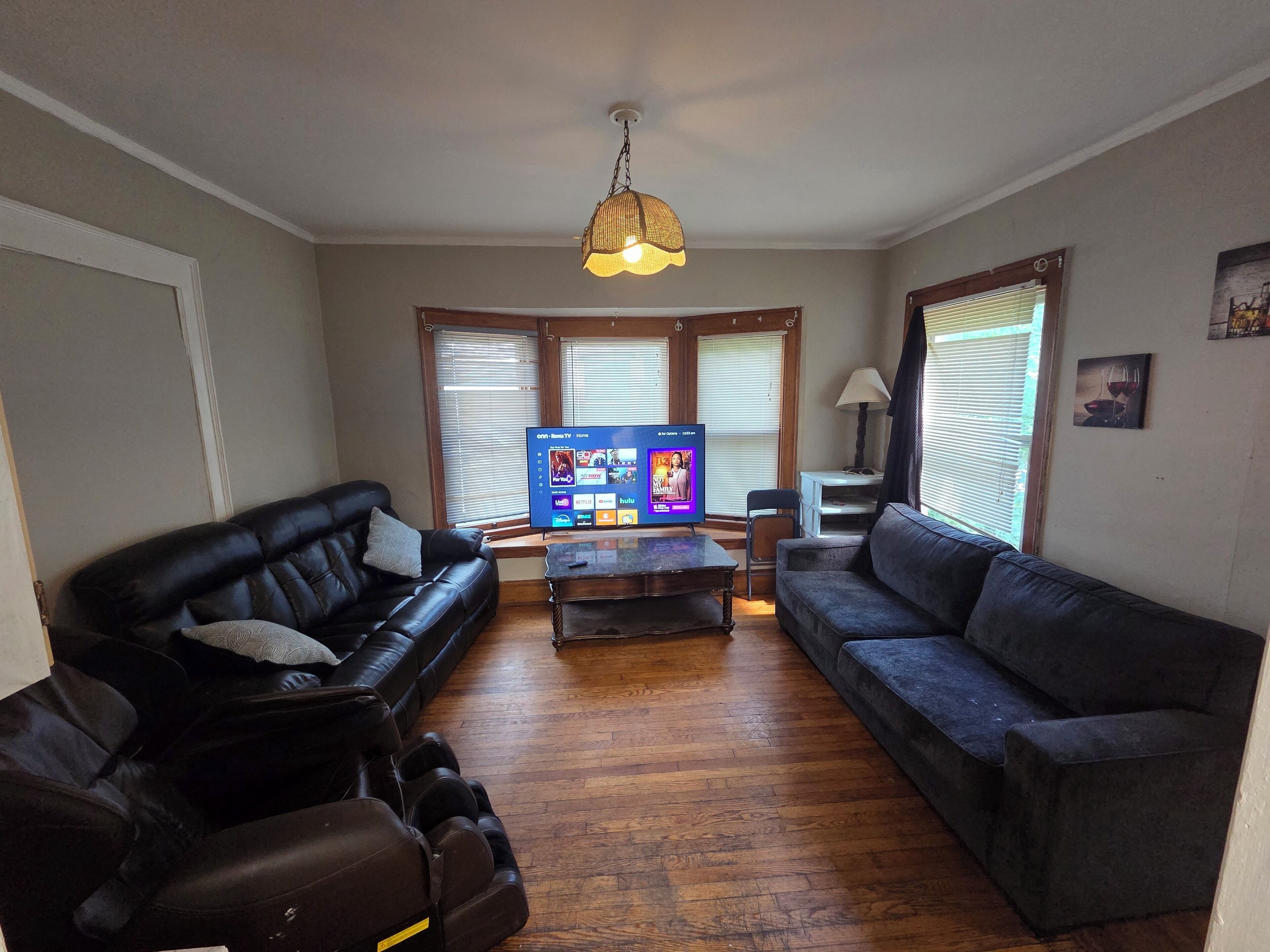 A living room with a flat-screen TV, two sofas, a coffee table, and a massage chair.