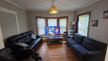 A living room with a flat-screen TV, two sofas, a coffee table, and a massage chair.