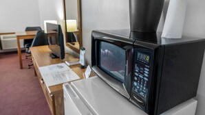A microwave oven with a digital display, a coffee maker, and a tissue roll on top. - Auburn Inn South (Auburn)