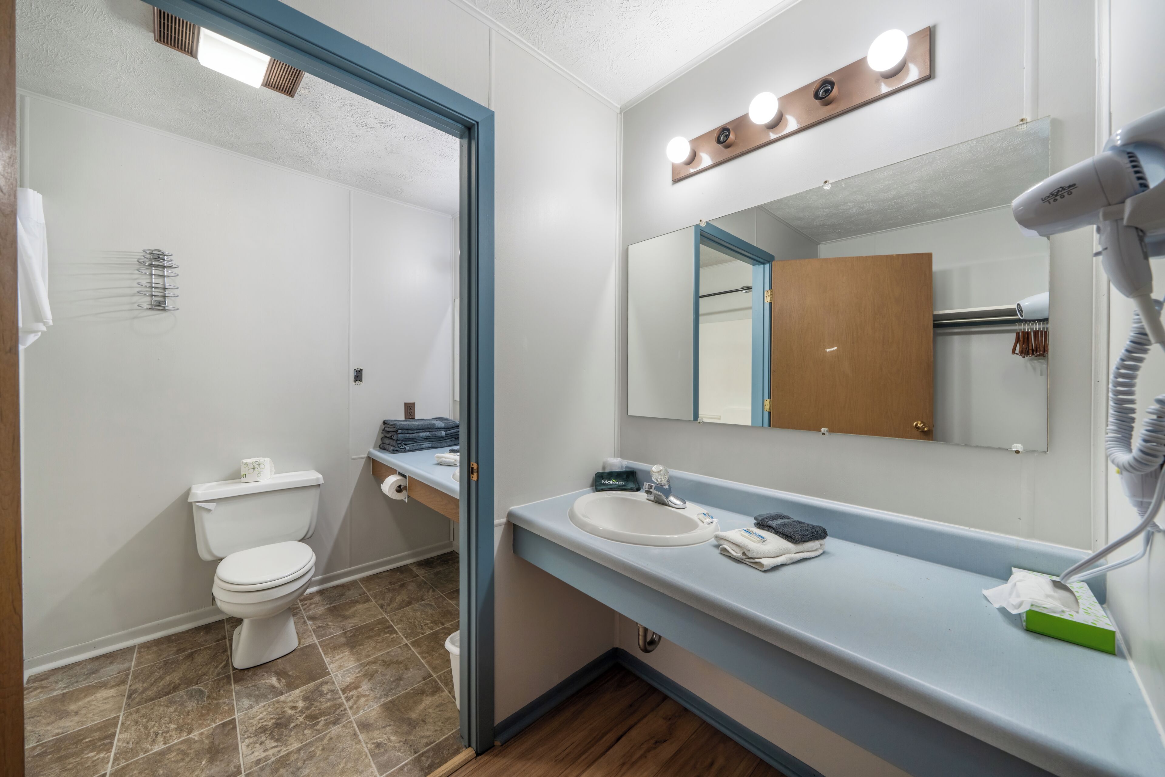 A bathroom with a toilet, sink, and mirror.