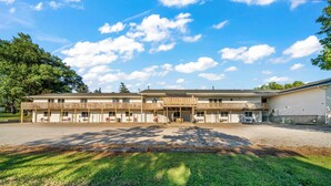 A motel with a central building and two wings, each with a covered parking area. - Auburn Inn South (Auburn)