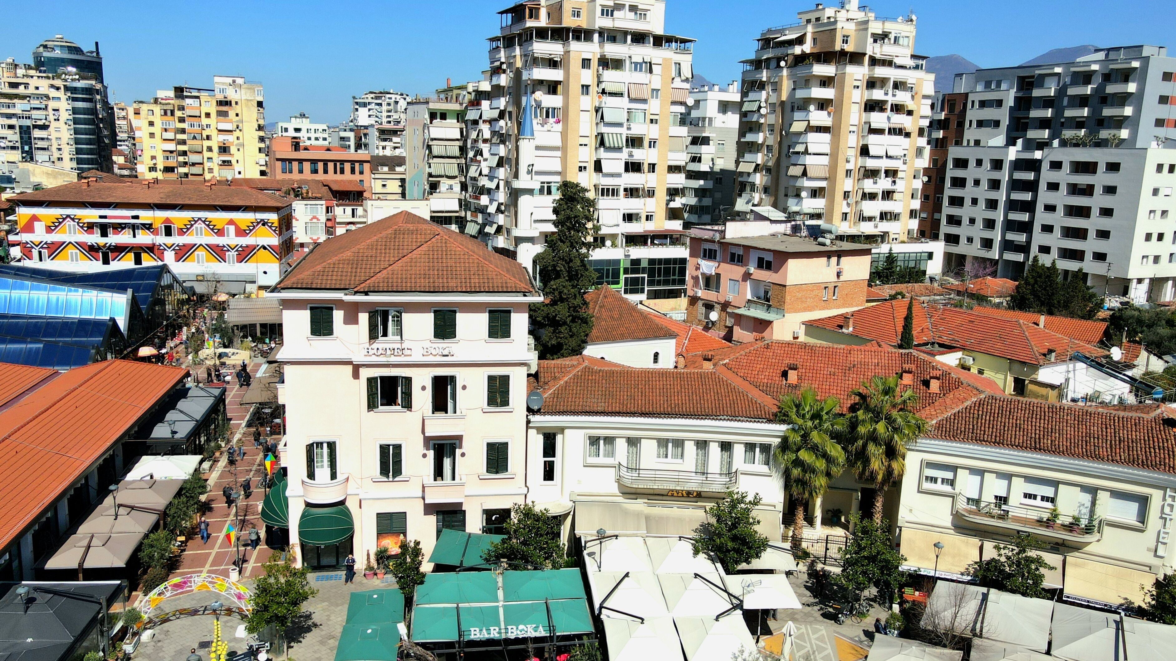 Un edificio a più piani con balconi, una terrazza sul tetto e una strada con caffè.