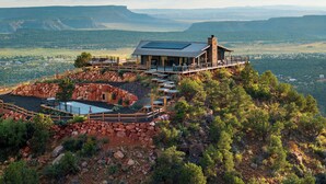 A mountain lodge with a deck overlooking a valley, surrounded by rocky terrain and sparse vegetation. - Elevation40Zion (Apple Valley)