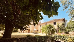 Un edificio in pietra con un cortile, un ponte e un albero.