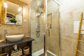 Un baño con ducha de vidrio, un lavabo blanco y un espejo con iluminación.