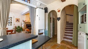 Una cocina con encimera, armarios y una escalera que lleva a otra habitación.