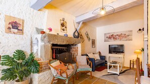 Una sala de estar acogedora con chimenea, asientos cómodos, un televisor y decoración en las paredes.