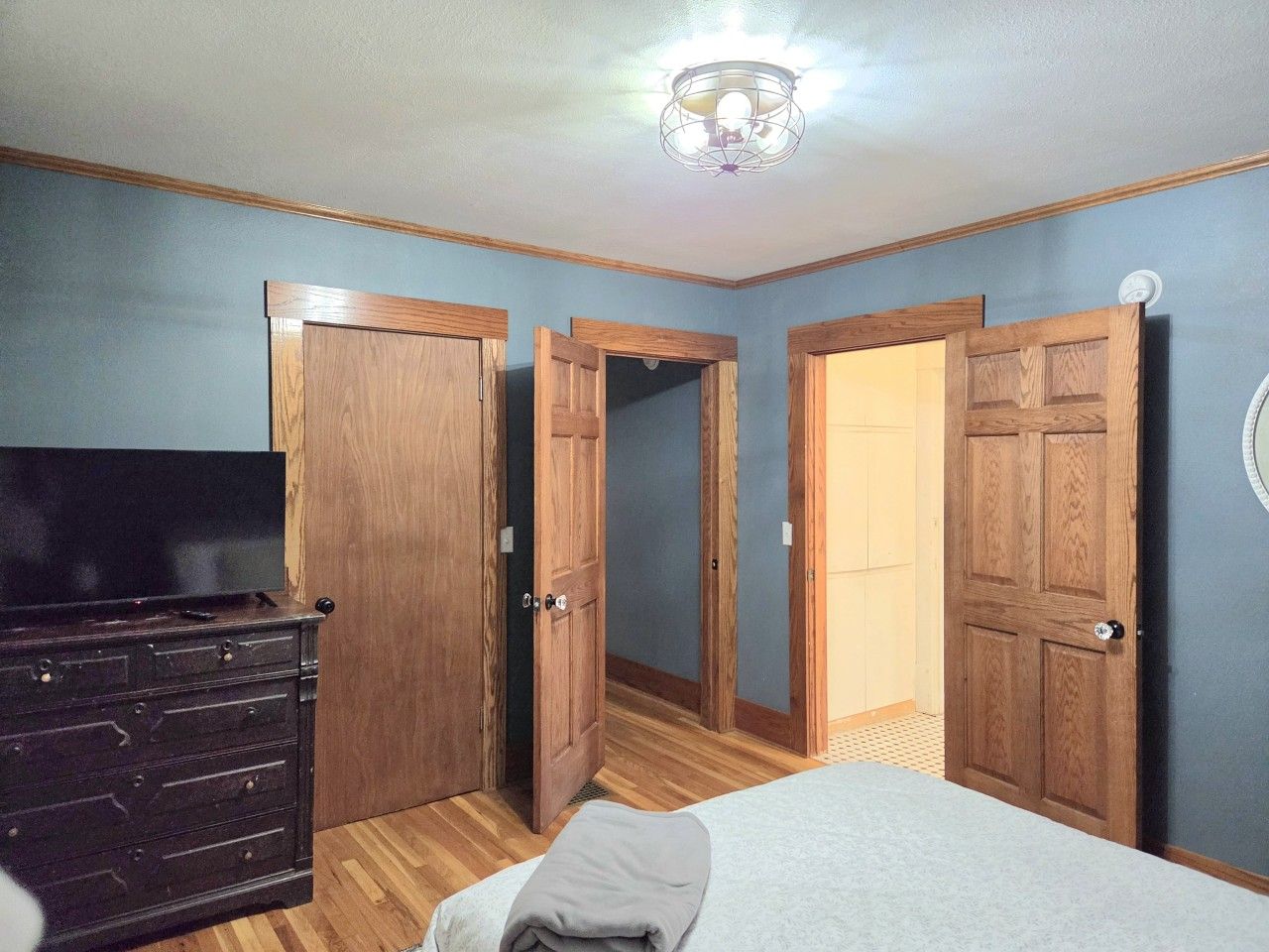 Une chambre à coucher avec un lit, une commode et trois portes en bois.