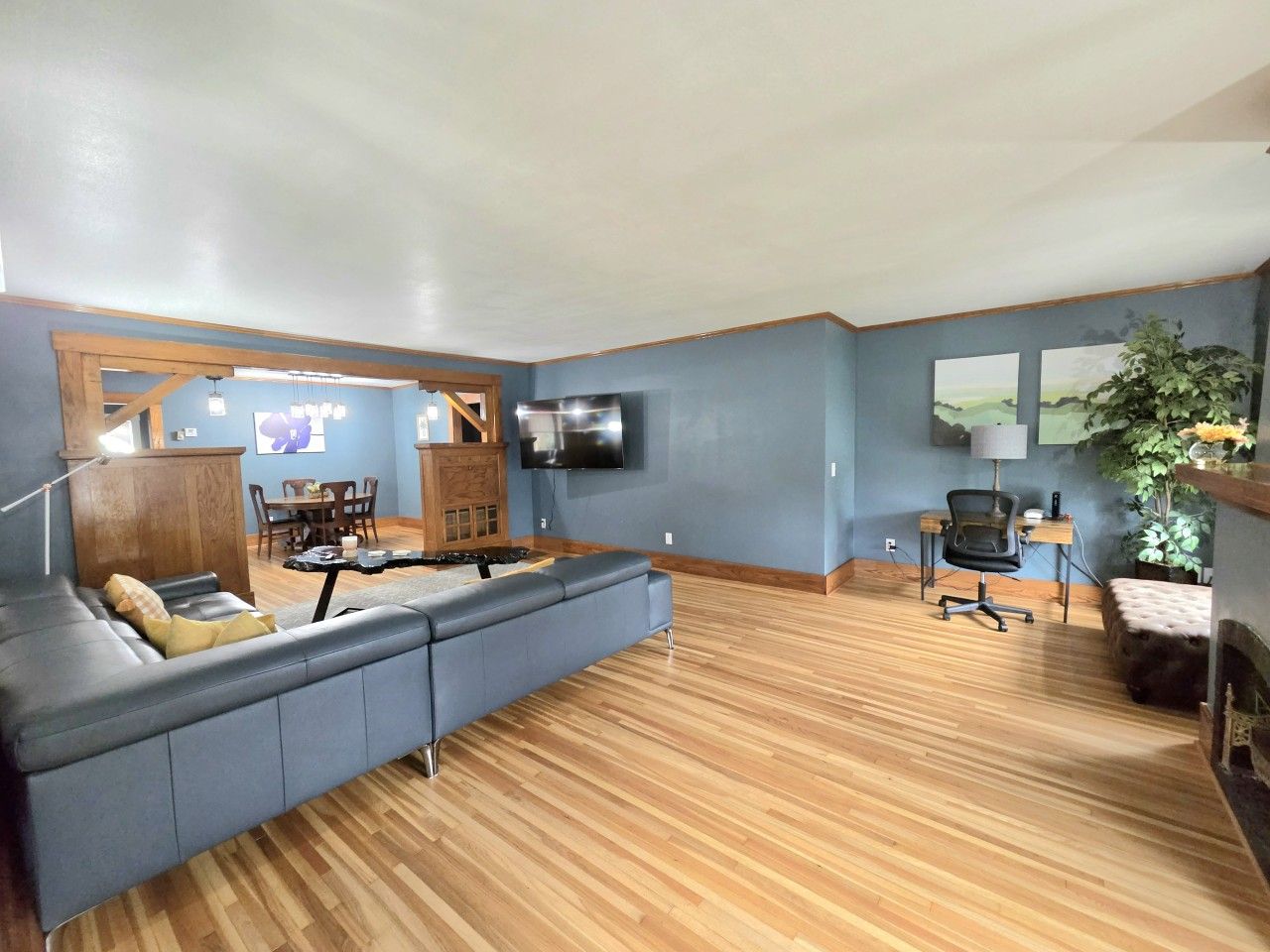 A spacious living room with a large sectional sofa, a dining area, and a television mounted on the wall.