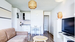 Un salon moderne comprenant un canapé, un téléviseur et un coin repas avec une table et des chaises.