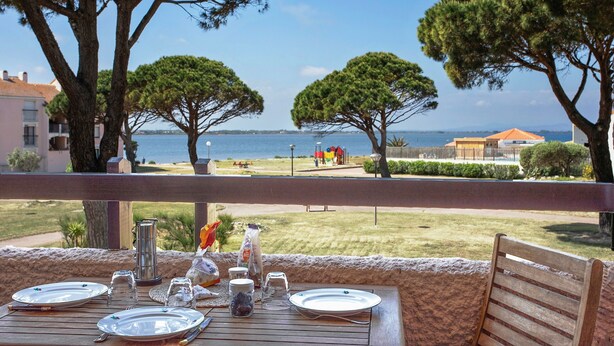 Une table dressée pour le dîner, avec vue sur la mer et les arbres.