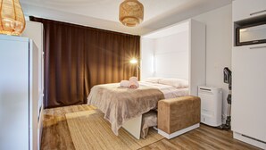 Une chambre à coucher moderne avec un lit, une table de chevet, une lampe et un aspirateur.