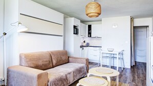 Un salon moderne avec un canapé, une table à manger et une cuisine en arrière-plan.