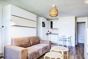Un salon moderne avec un canapé, une table à manger et une cuisine en arrière-plan.