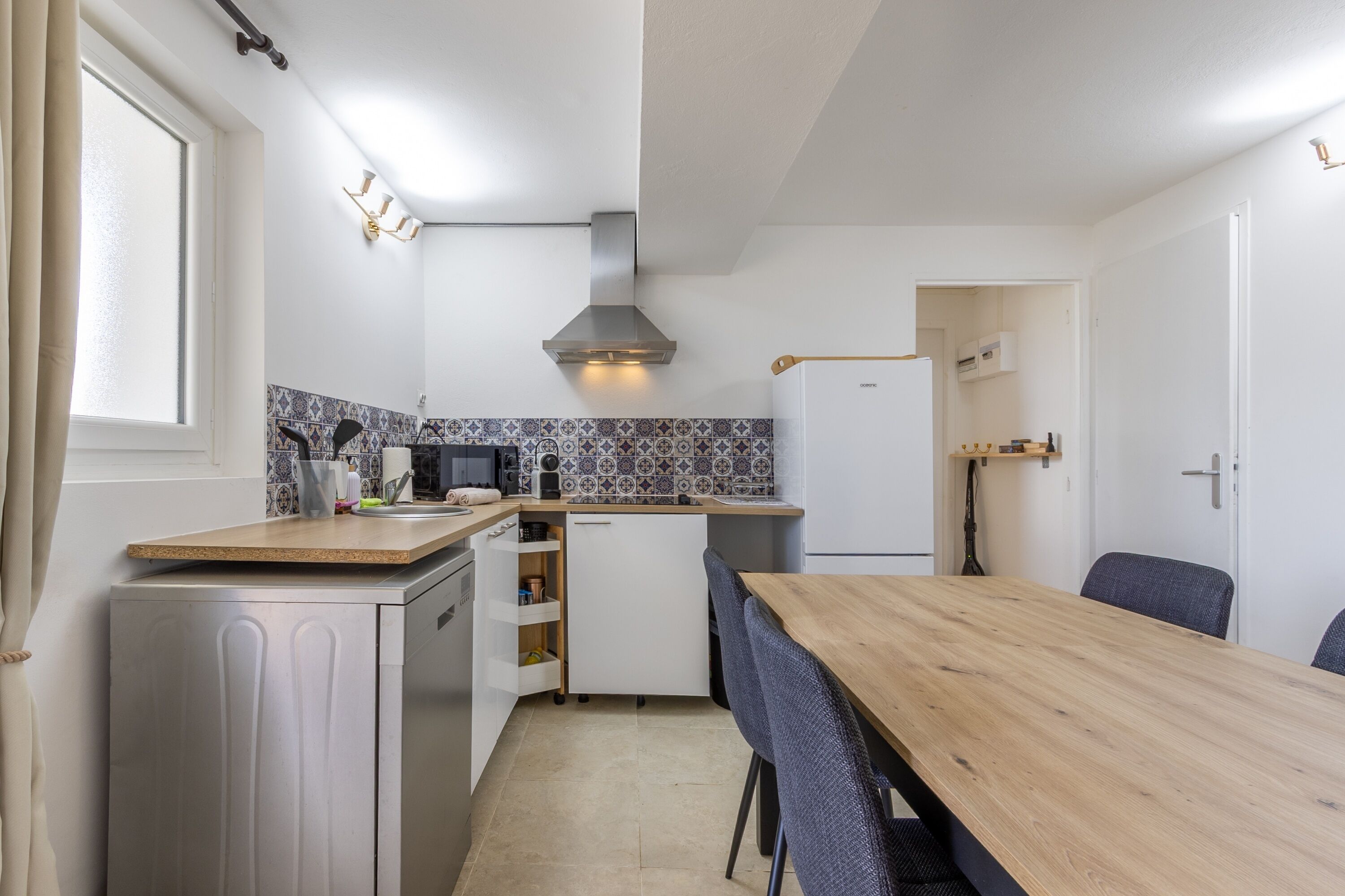 A compact kitchen with a wooden table, white cabinets, and a microwave.