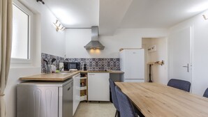 Una cocina compacta con una mesa de madera, armarios blancos y un microondas.
