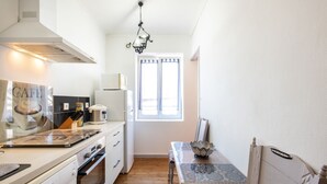 Cucina con piano cottura, forno e finestra con tende.