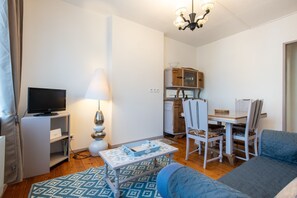 A living room with a television, a lamp, a dining table with chairs, and a sofa. - Le Nid de Boulogne - À 2 km de la plage (Boulogne-Sur-Mer)