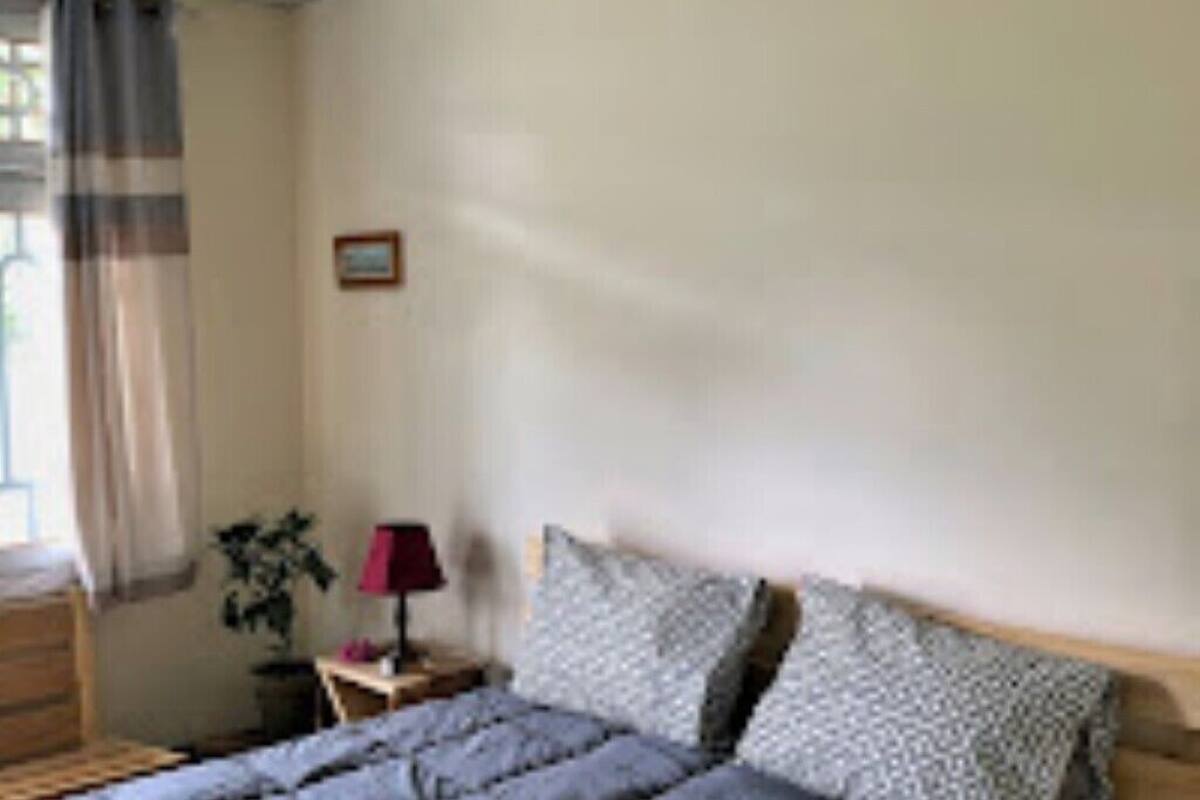 A bedroom with a bed, a nightstand, a lamp, and a framed picture on the wall.