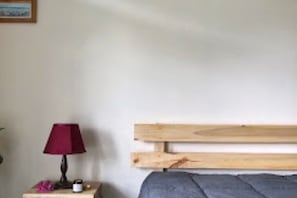 Une chambre à coucher avec une tête de lit en bois, une table de chevet avec une lampe et un petit objet décoratif.