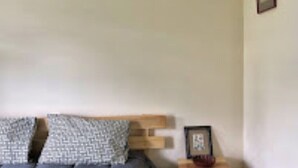 A bedroom with a bed, pillows, a wooden headboard, a bedside table, and a framed picture. - Asqur Bassi (Mekhtar)