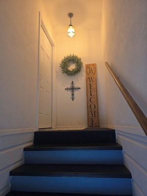Eine Treppe mit einem 'WELCOME'-Schild, einem Kreuz und einem Kranz.
