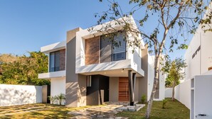A modern two-story house with a stone pathway leading to the entrance, surrounded by greenery and a clear sky. - Casa Brisa, Playa del Carmen (Playa del Carmen)