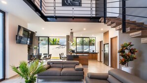 A modern living room with a sofa, a coffee table, and a TV. There is a staircase leading to an upper level. - Casa Brisa, Playa del Carmen (Playa del Carmen)