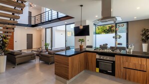 A modern kitchen with a central island, built-in appliances, and a dining area with sofas. - Casa Brisa, Playa del Carmen (Playa del Carmen)