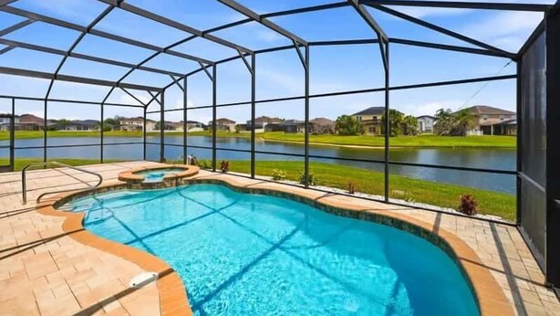 A pool area with a clear view of a lake and houses in the background. - Family Home with Private Pool Near Disney (Kissimmee)