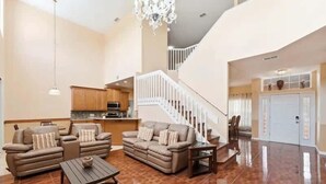 A spacious living area with a sofa set, a dining table, and a staircase leading to an upper floor. - Family Home with Private Pool Near Disney (Kissimmee)