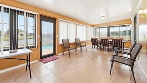 A spacious indoor area with a dining table and chairs, large windows with blinds, and a door with a metal grille. - Family Home with Private Pool Near Disney (Kissimmee)