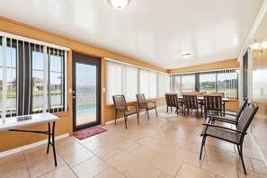 A spacious indoor area with a dining table and chairs, large windows with blinds, and a door with a metal grille. - Family Home with Private Pool Near Disney (Kissimmee)