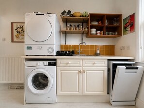 A kitchen with a washing machine, a dryer, and a sink.