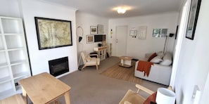 A living room with a fireplace, a sofa, a coffee table, and a bookshelf. - Coastal Retreat Herne Bay Near Beach and Cafes (Auckland)