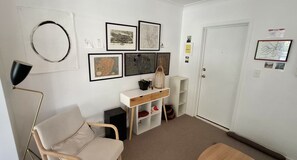 A room with a desk, chair, and a door. There are framed pictures on the wall. - Coastal Retreat Herne Bay Near Beach and Cafes (Auckland)
