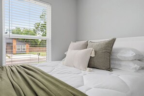 Ein Schlafzimmer mit Bett, Kissen und einem Fenster mit Jalousien.