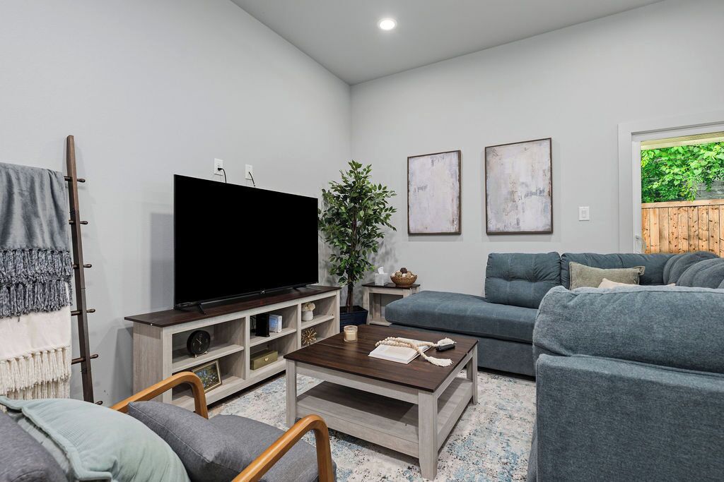 Ein Wohnzimmer mit Flachbildfernseher, einer Couch, einem Couchtisch und einer Pflanze.