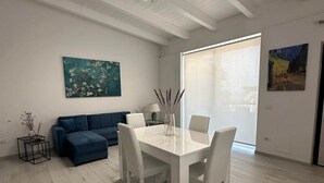 Una sala de estar moderna con una mesa de comedor blanca, sofá azul y obras de arte en las paredes.