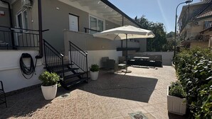 Un edificio con patio empedrado, mobiliario exterior y plantas en macetas.