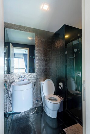 A modern bathroom with a toilet, bidet, and shower.