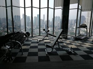 A gym with exercise equipment, large windows, and a city view.