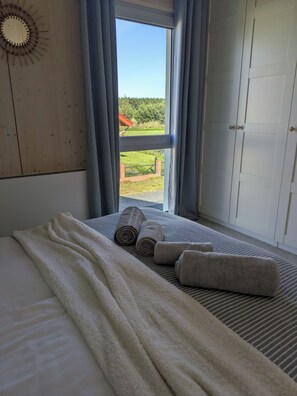 Une chambre à coucher avec un lit, une fenêtre avec des rideaux et une vue sur un paysage verdoyant.