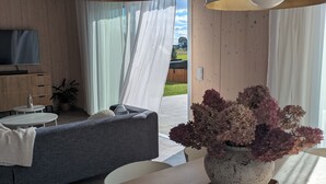 A modern living room with a sofa, dining table, and a TV. - Scandinavian Villa with sauna and hot tube and big garden. (Kołczewo)