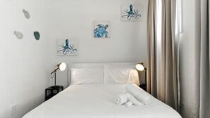 A neatly made bed with white linens, two bedside lamps, and artwork on the wall. - 1BR 1BA Sleeps 2 Wi-Fi La Placita (San Juan)