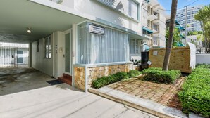 A modern hotel entrance with a covered driveway, a sign indicating the property name, and a gated parking area. - 1BR 1BA Sleeps 2 Wi-Fi La Placita (San Juan)