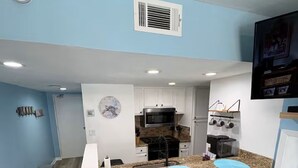 Una cucina compatta con isola centrale, pensili bianchi e forno a microonde integrato.